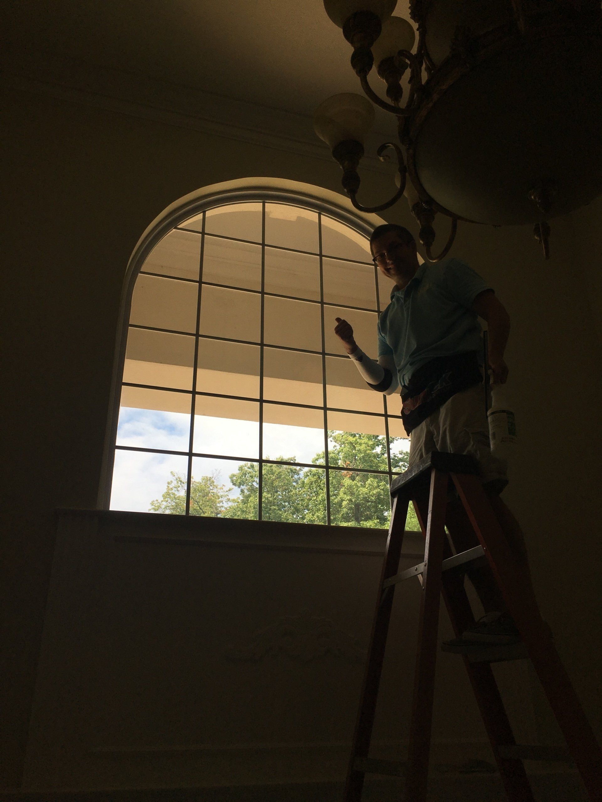 A man standing on a ladder in front of a window