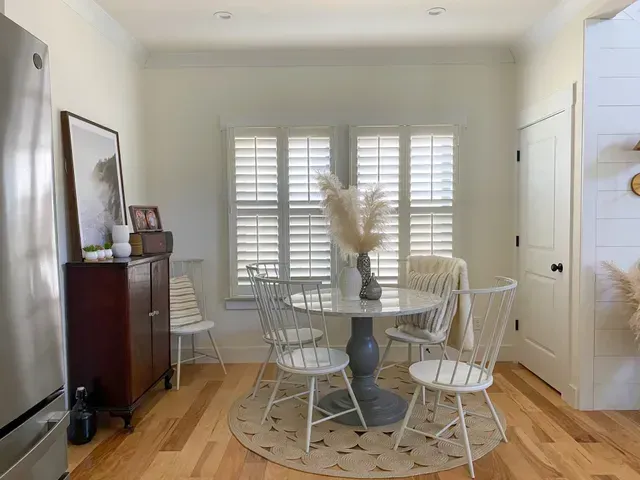 A dining room with a table and chairs and a refrigerator.