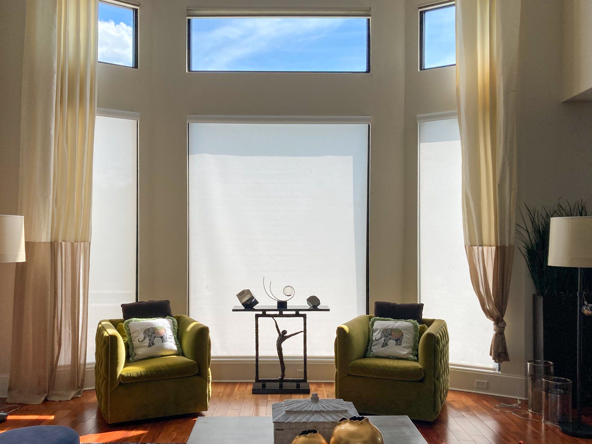 A living room with two green chairs and a large window