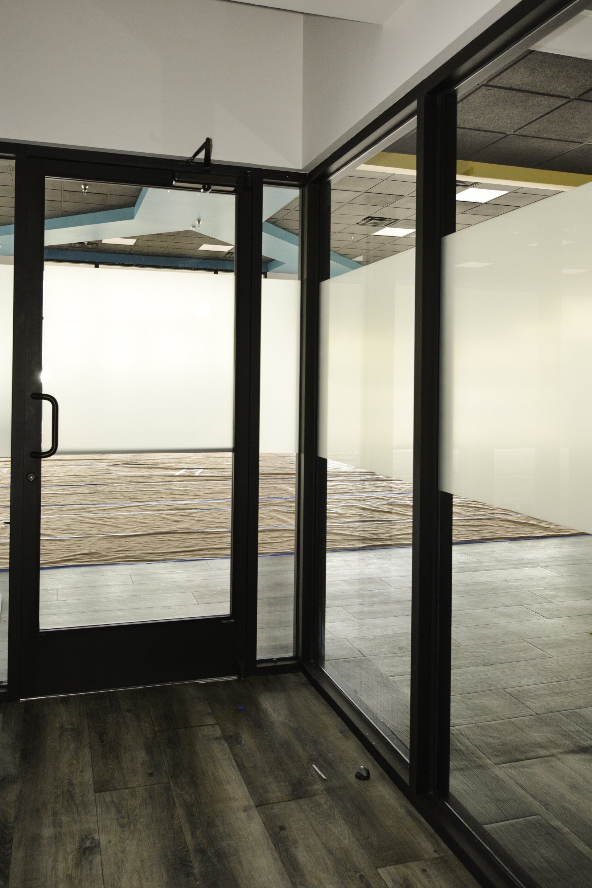 An empty room with a black door and glass walls