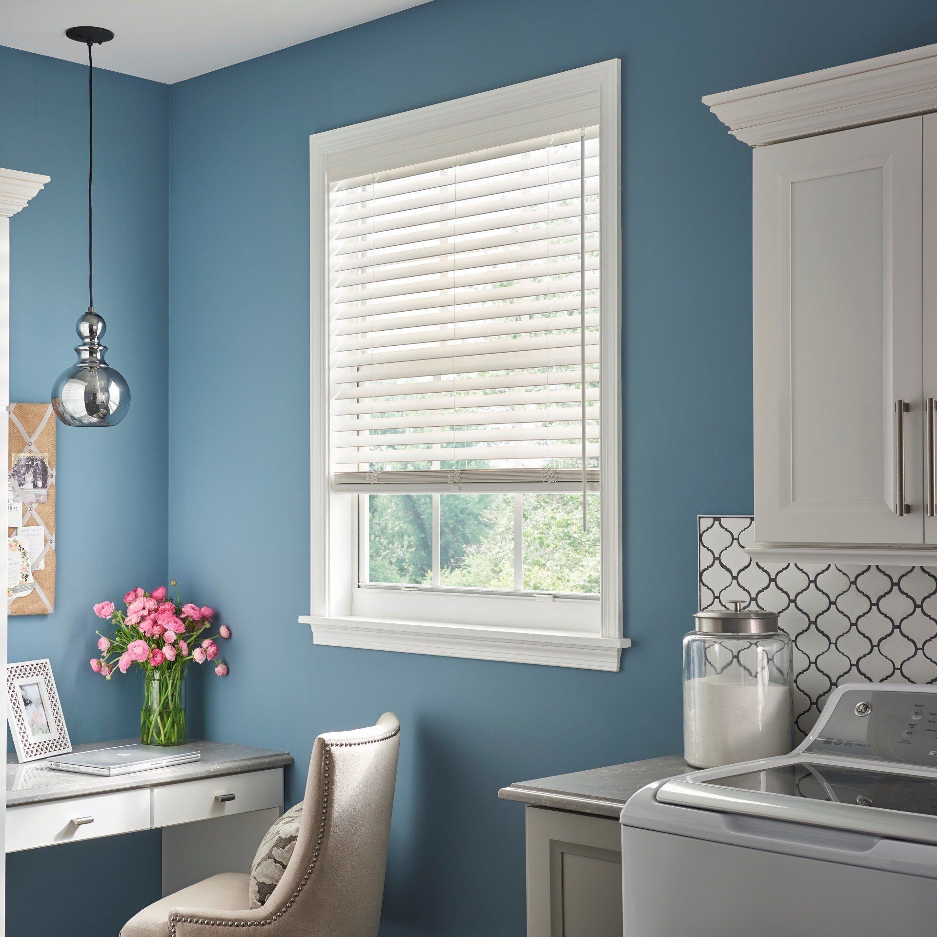 A laundry room with blue walls and white cabinets