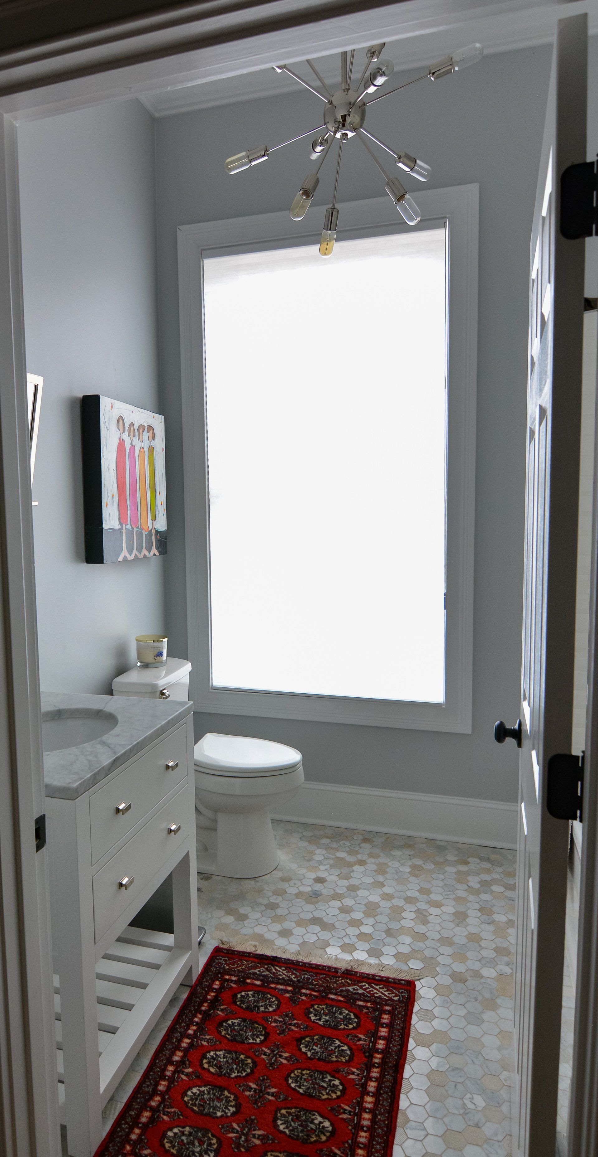 A bathroom with a toilet , sink , and window.