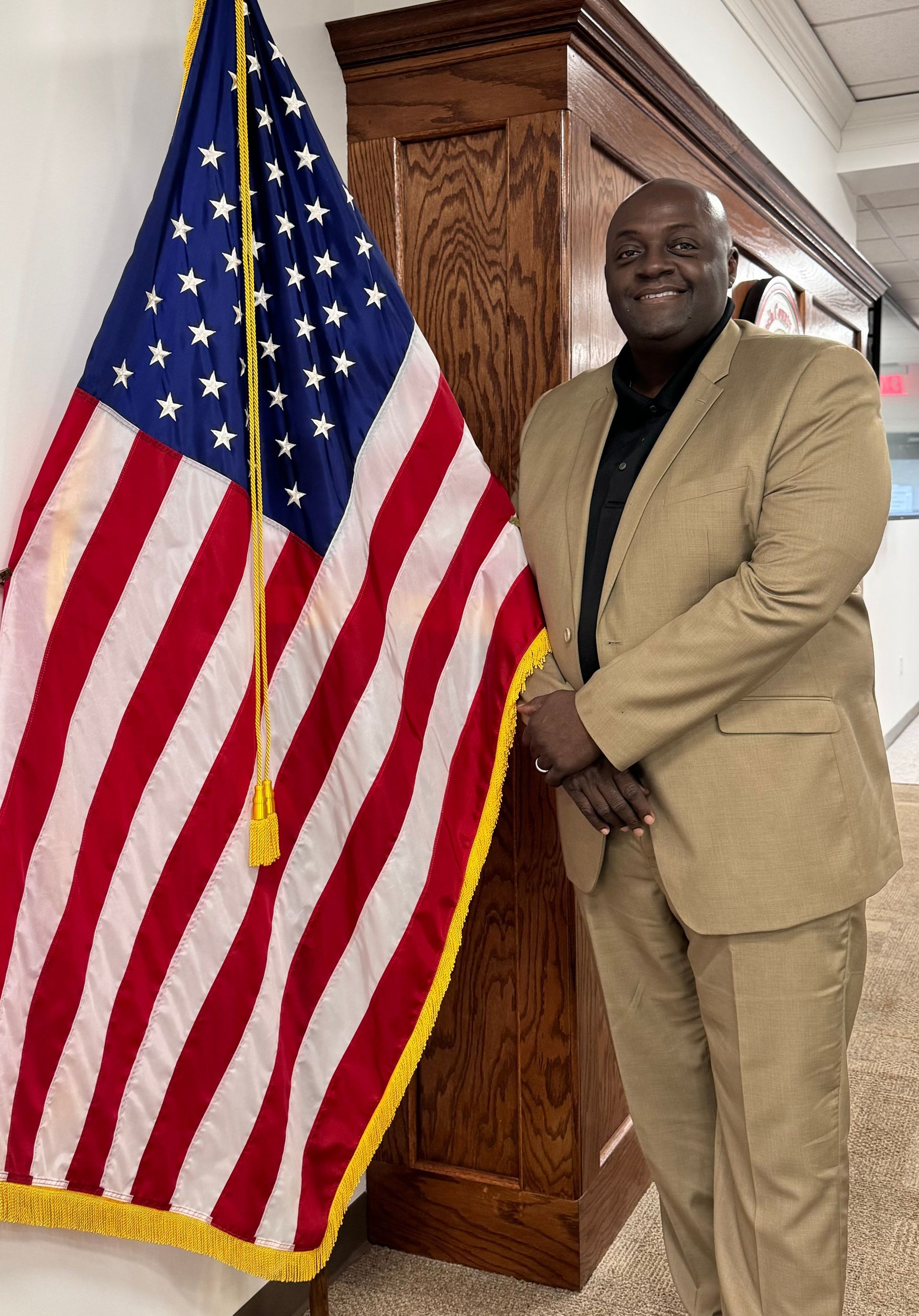 A man in a suit and tie is standing in front of an american flag.