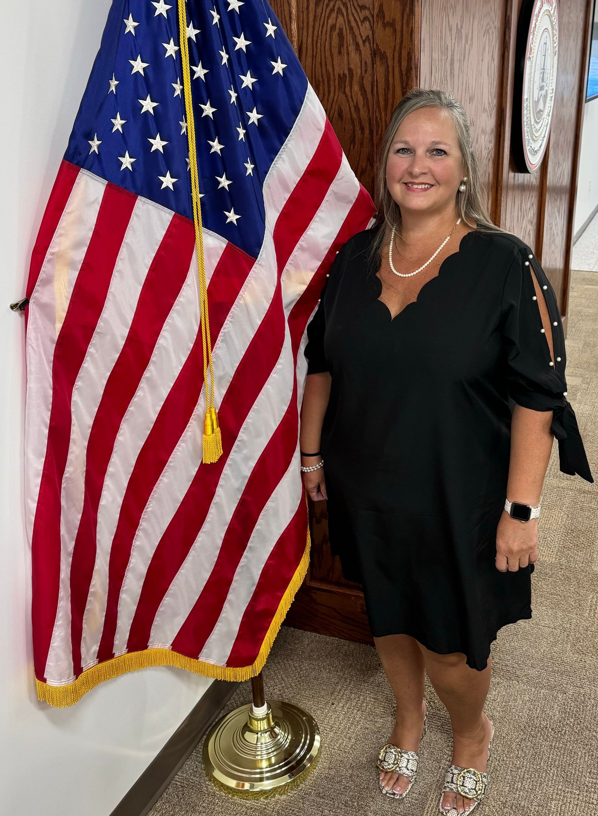 A woman is standing in front of an american flag.