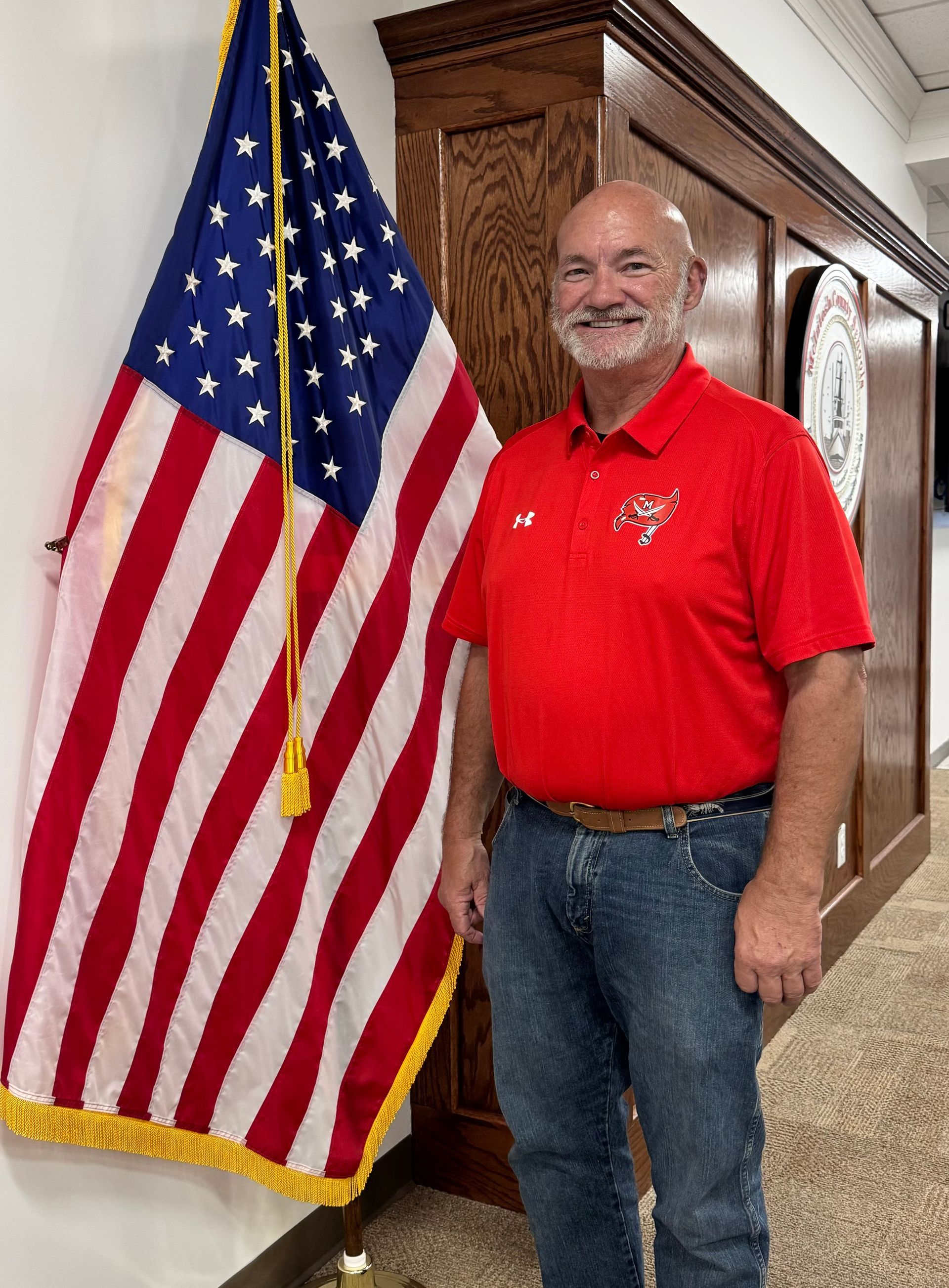 A man in a suit and tie is standing in front of an american flag.