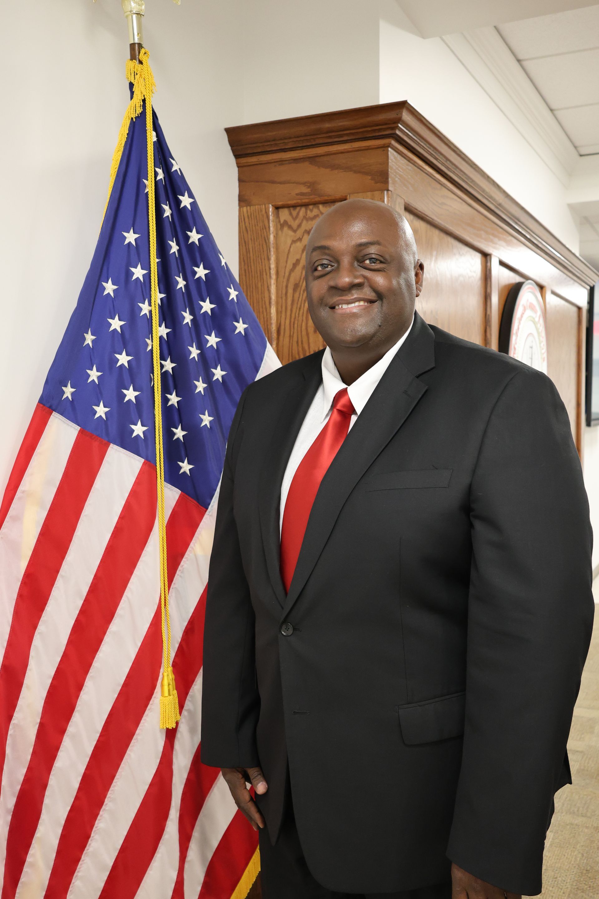 A man in a suit and tie is standing in front of an american flag.