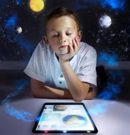 A young boy laying on the floor looking at a tablet