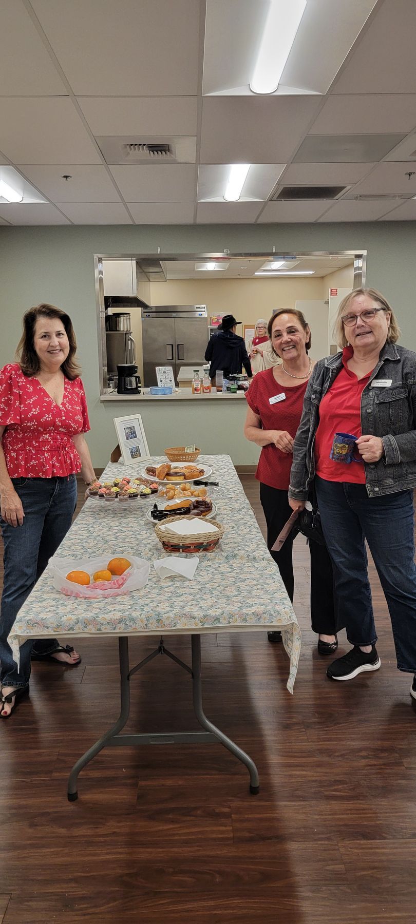 Four people standing behind a buffet table with desserts in a meeting room
