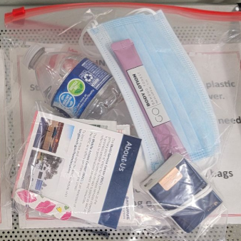 Clear zip bag of assorted personal care items, including a blue mask, lotion, and packaged supplies