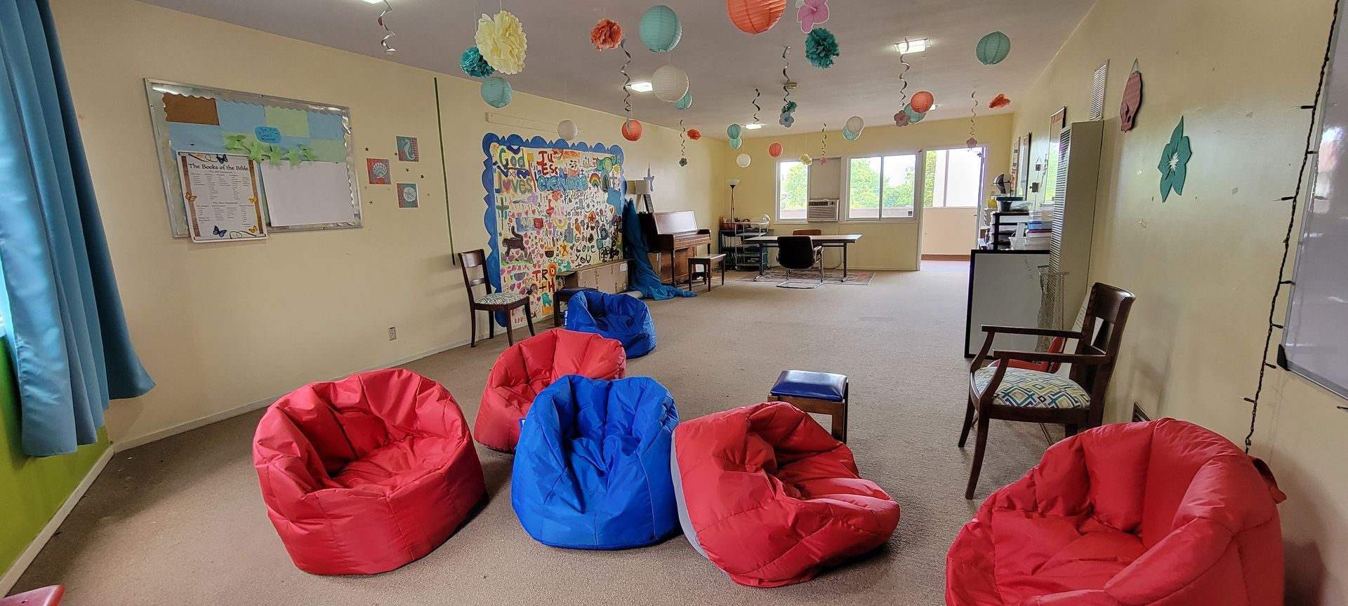 Bright classroom with colorful beanbag chairs, tables, wall art, and daylight from windows