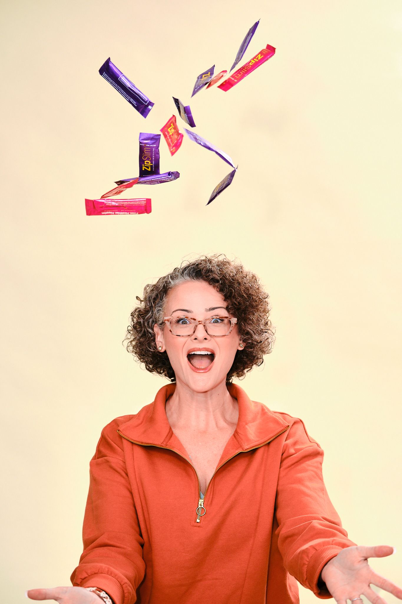 A person in an orange shirt looks up with excitement as various colorful snack bars float in the air above them.