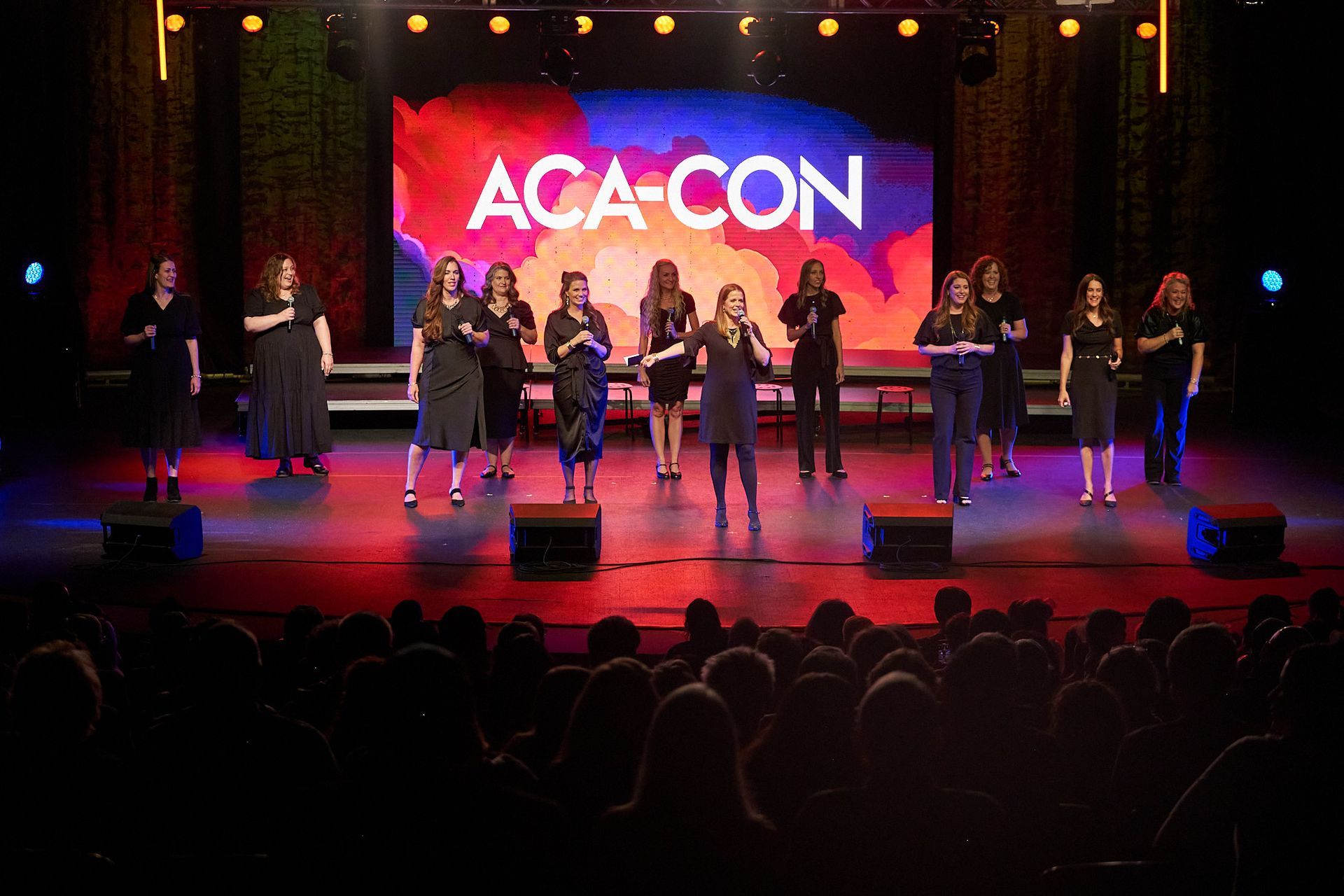 A vocal group performs on a stage with a brightly colored 
