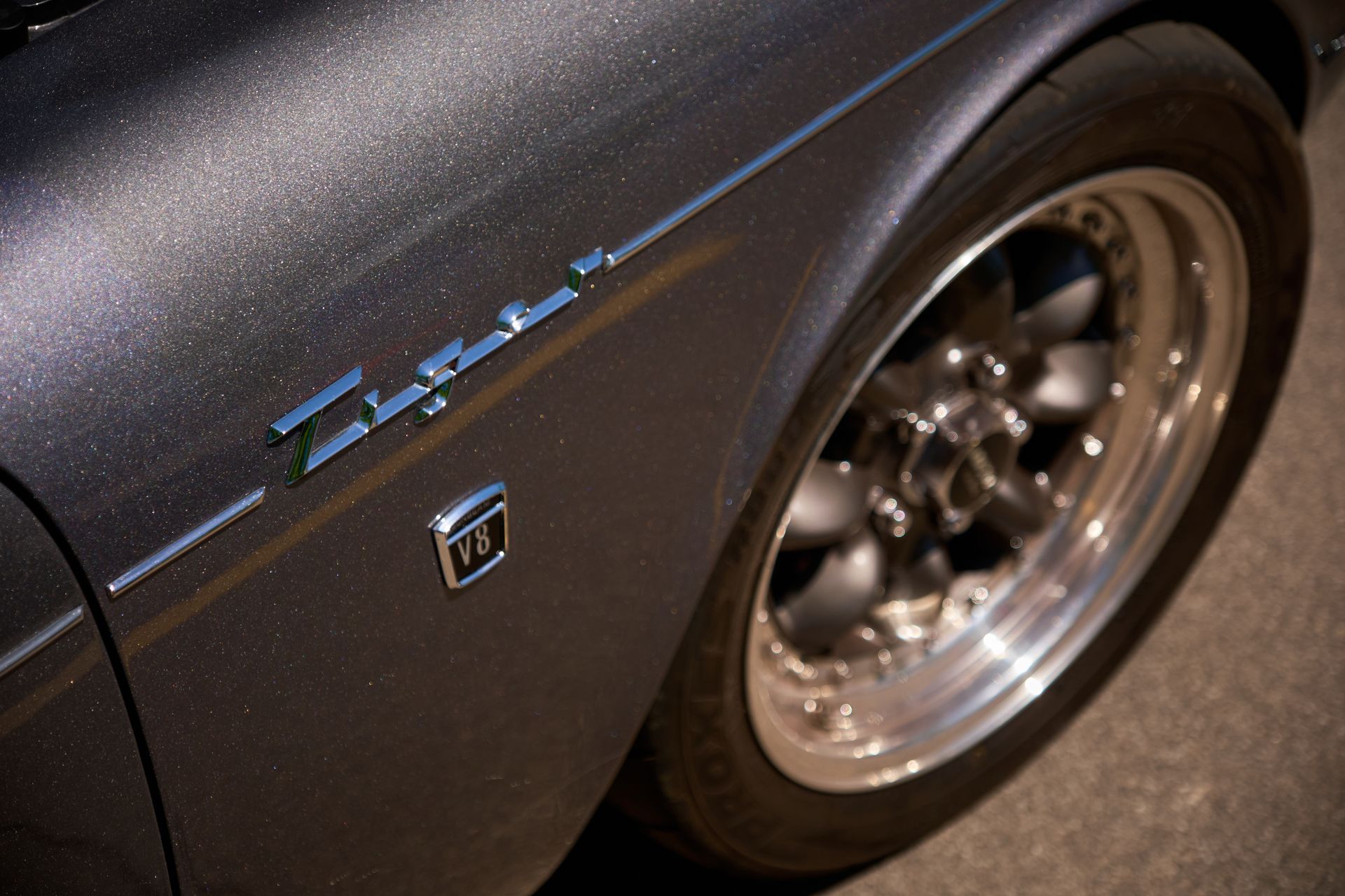 A close-up of a dark grey car fender with a silver 