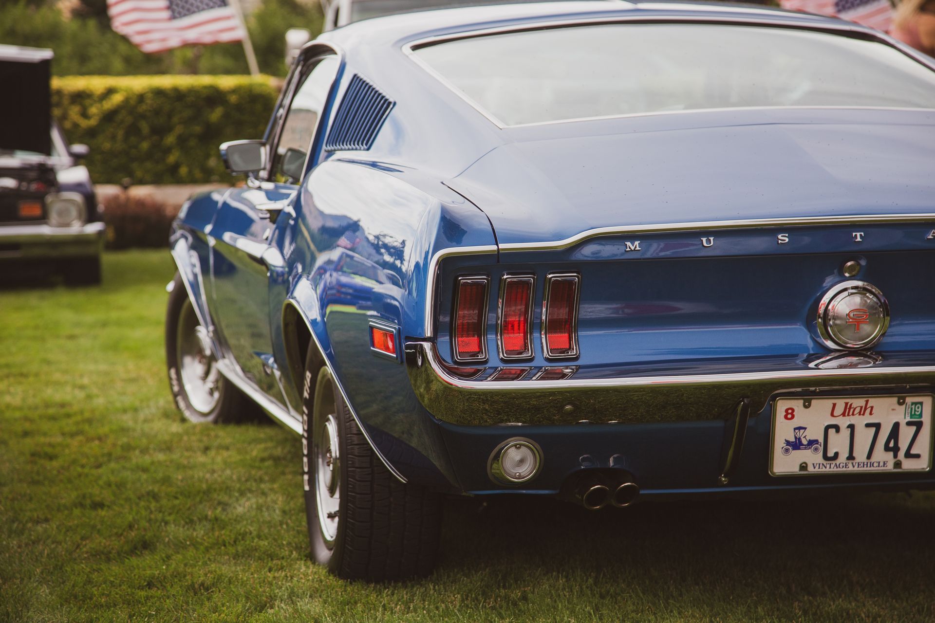 A blue vintage Ford Mustang parked on grass at an outdoor car show.