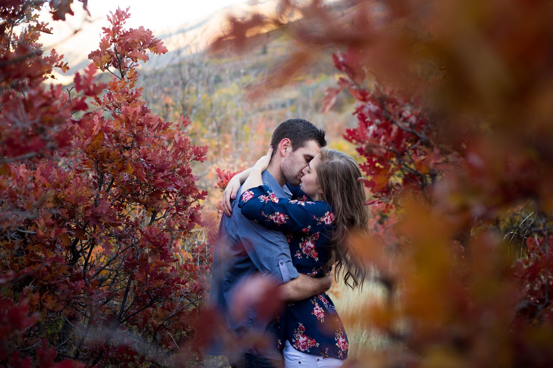 Two people smiling and hugging in front of a gray.