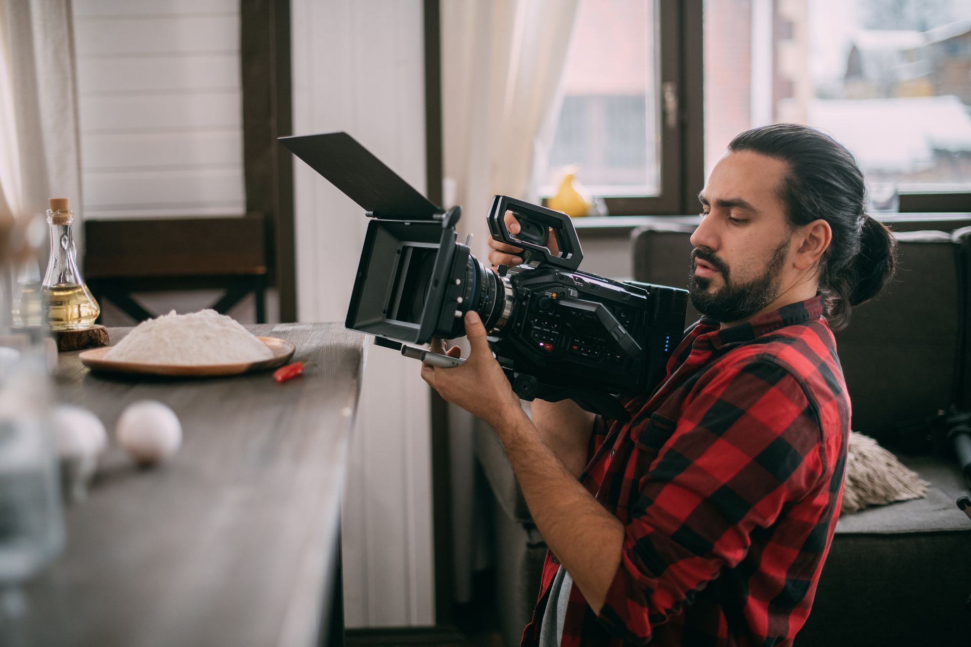 Man filming food on a countertop with a professional camera.