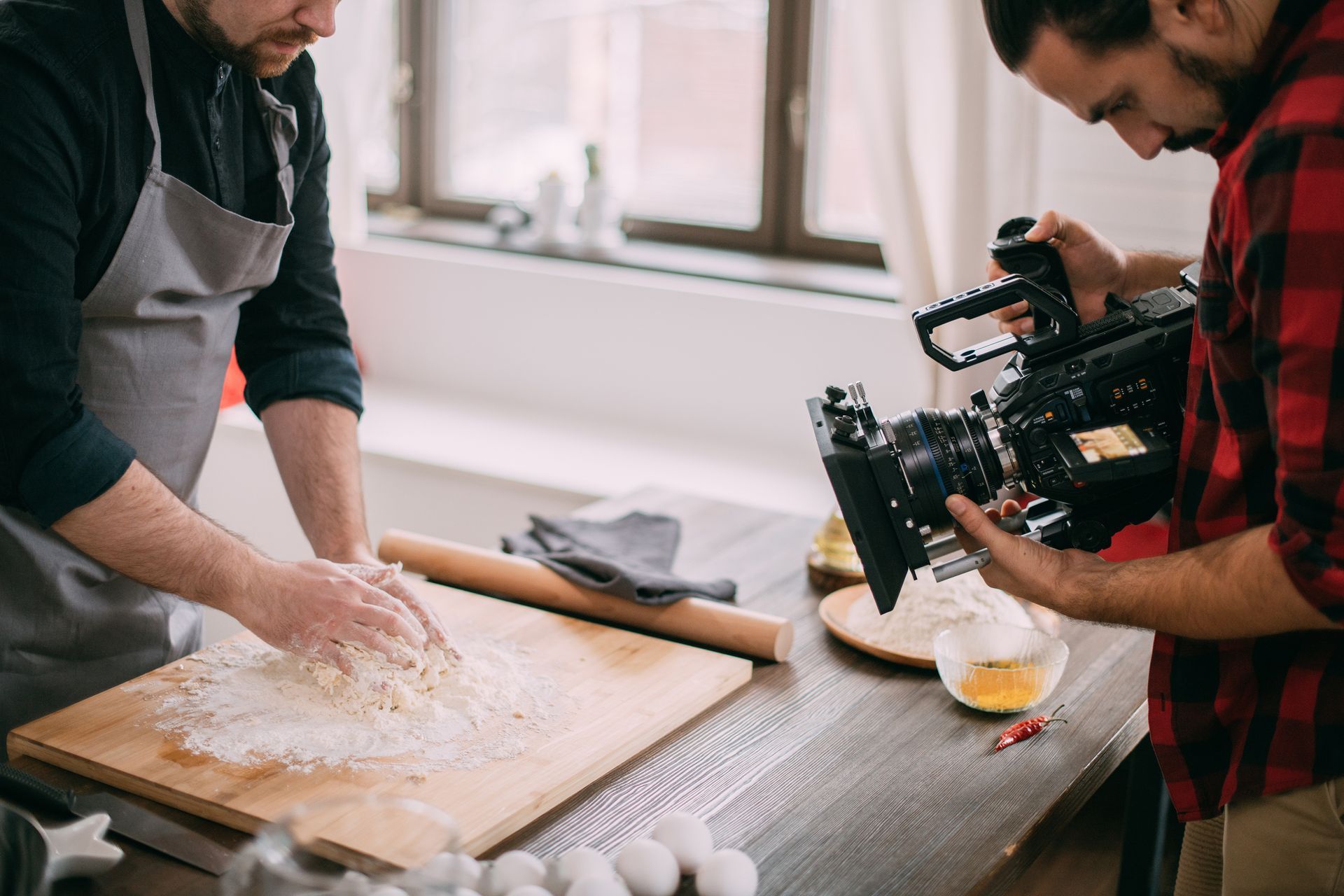 Chef kneading dough on a wooden board.