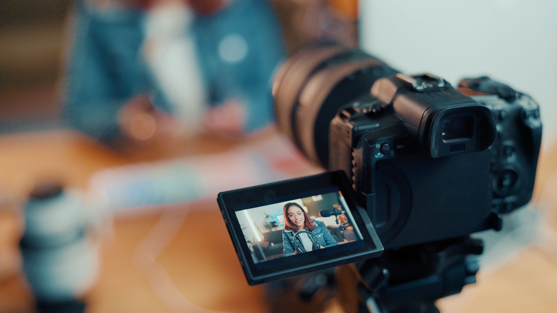 Camera on tripod filming a person.