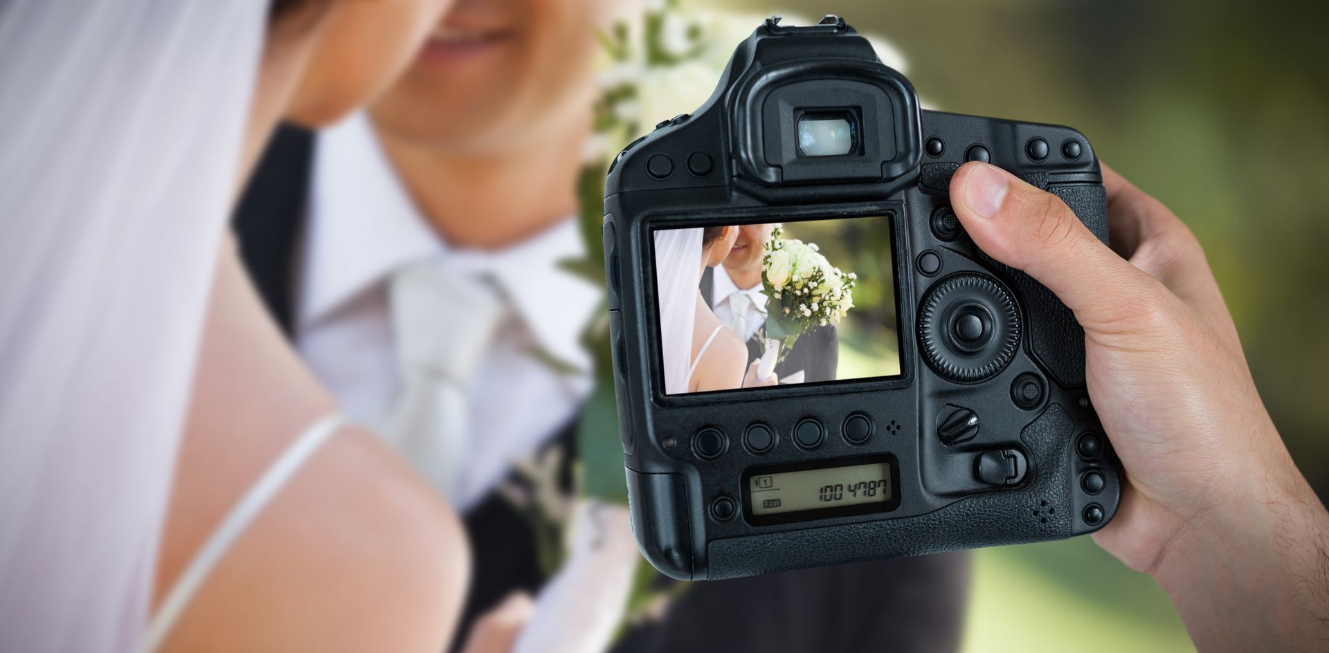 A photographer taking a photo of a wedding couple kissing.