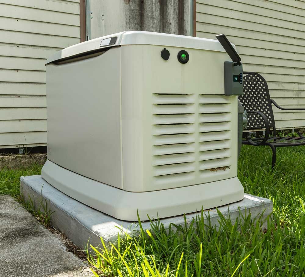 A beige standby generator on a concrete pad outside a building, with a green light illuminated.