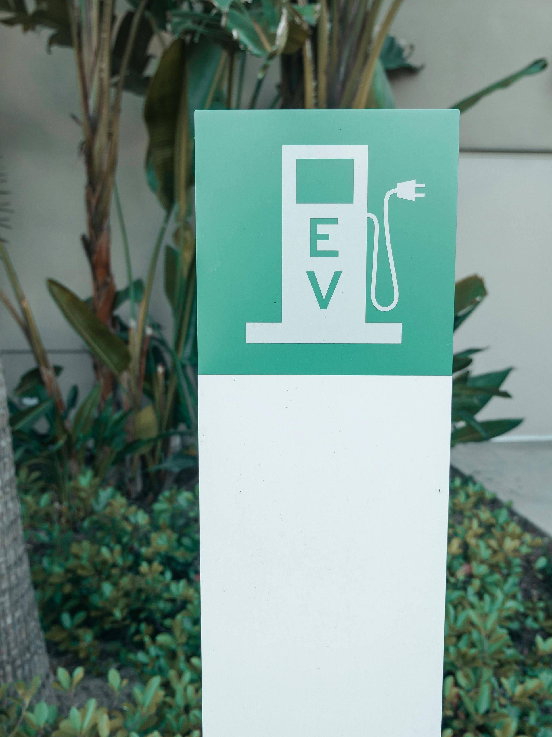Electric vehicle charging station sign; green and white, outdoors.