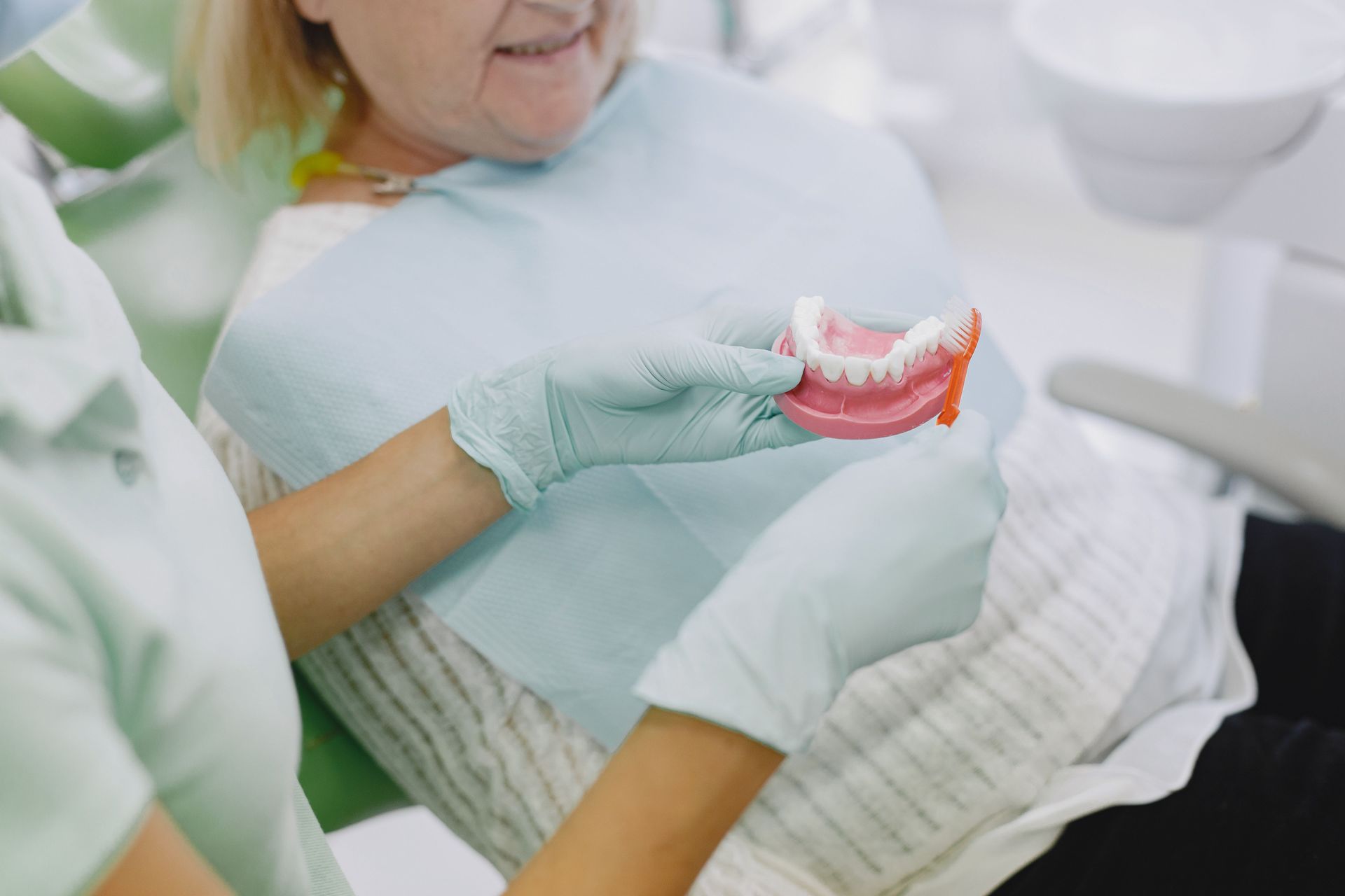 Dentist holding a denture while examining a patient in a dental chair