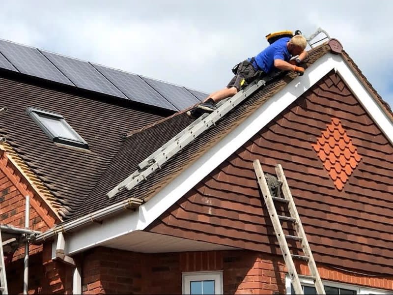 close-up of man in blue working on a roof