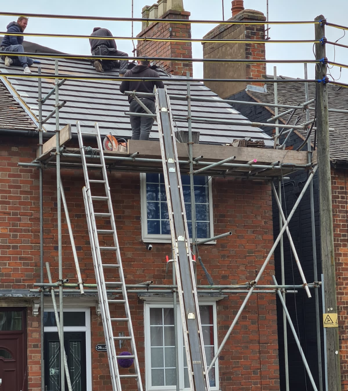 man working on roof clad in scaffolding
