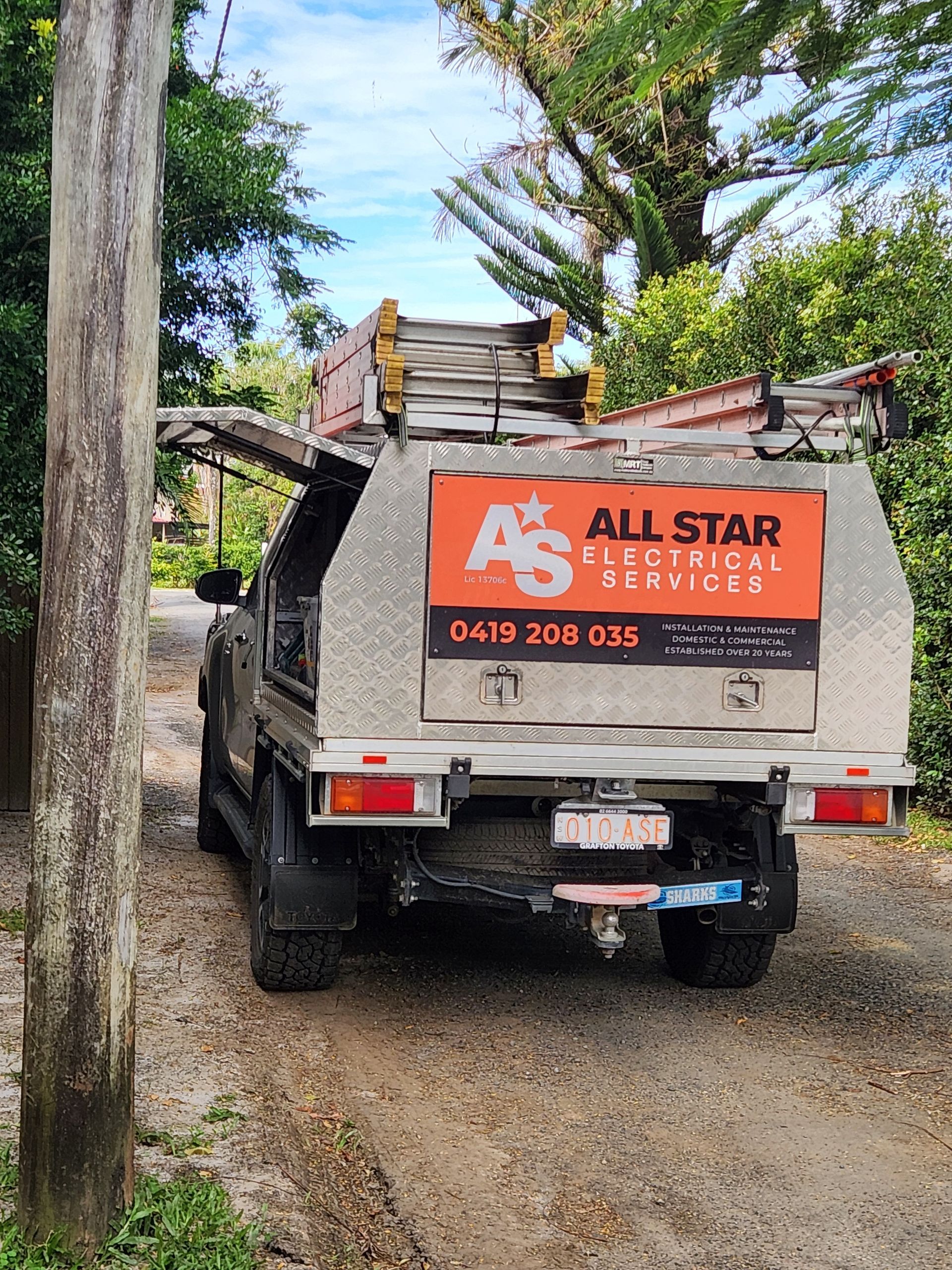 A Silver Truck with A Canopy on The Back Is Parked in A Field — All Star Electrical Services in Horsley, NSW