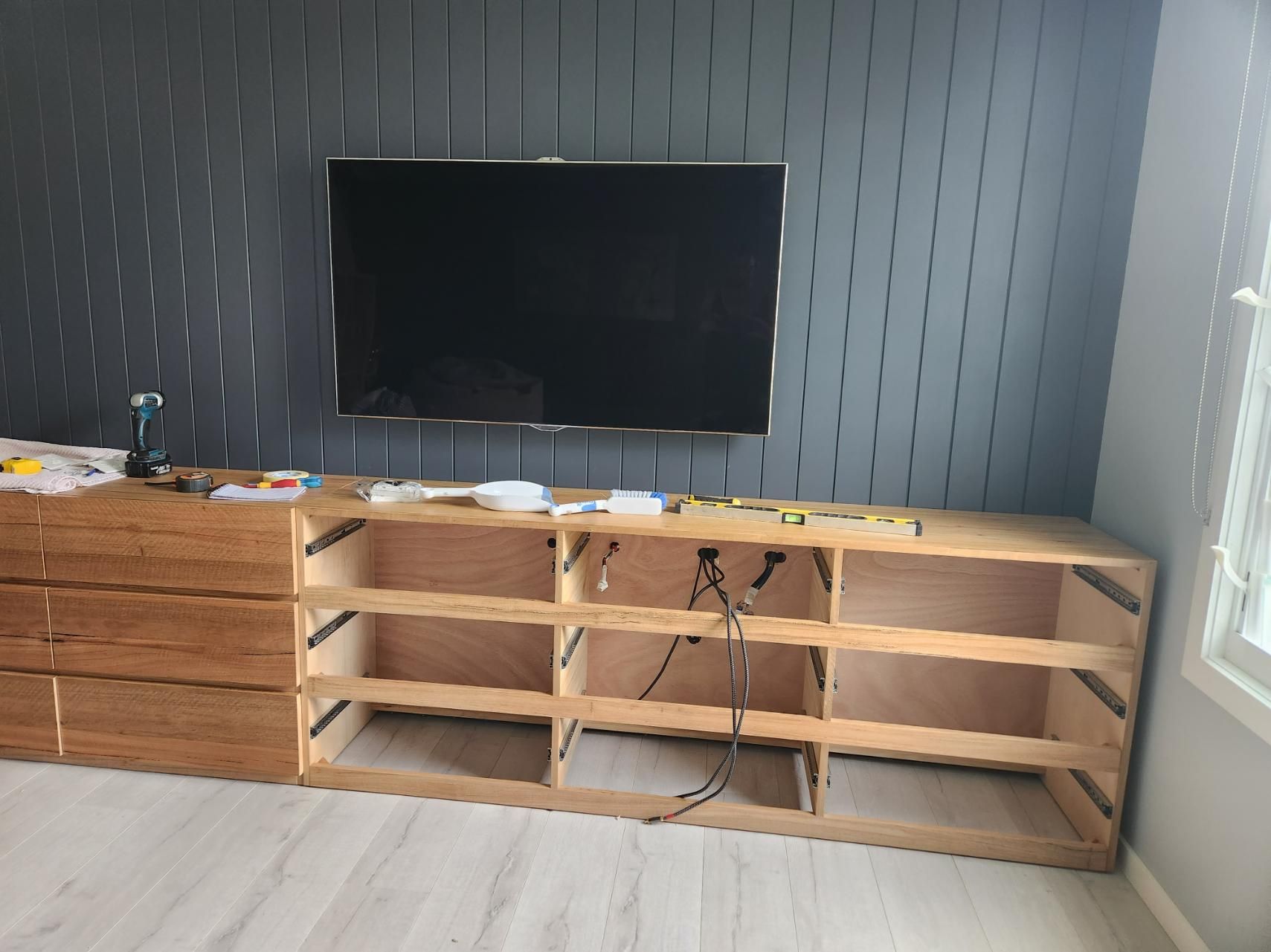A Flat Screen Tv Is Mounted on A Wall Above a Wooden Entertainment Center — All Star Electrical Services in Horsley, NSW
