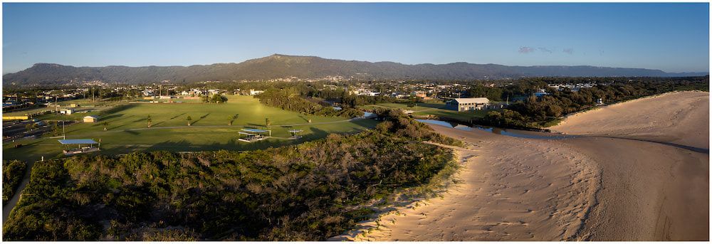 An Aerial View Of A Dirt Road Going Through A Lush Green Field — All Star Electrical Services in Corrimal, NSW