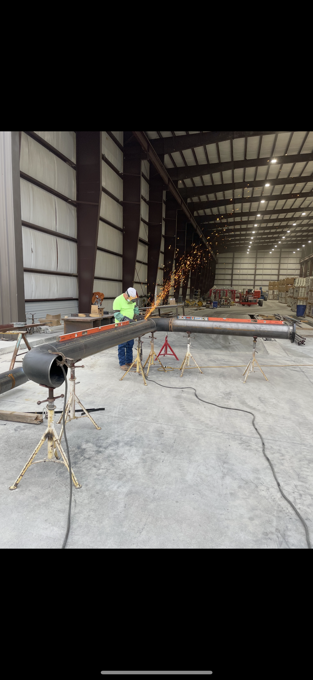 A person welding metal pipes inside an industrial warehouse. Sparks fly from the welding torch in Las Vegas.