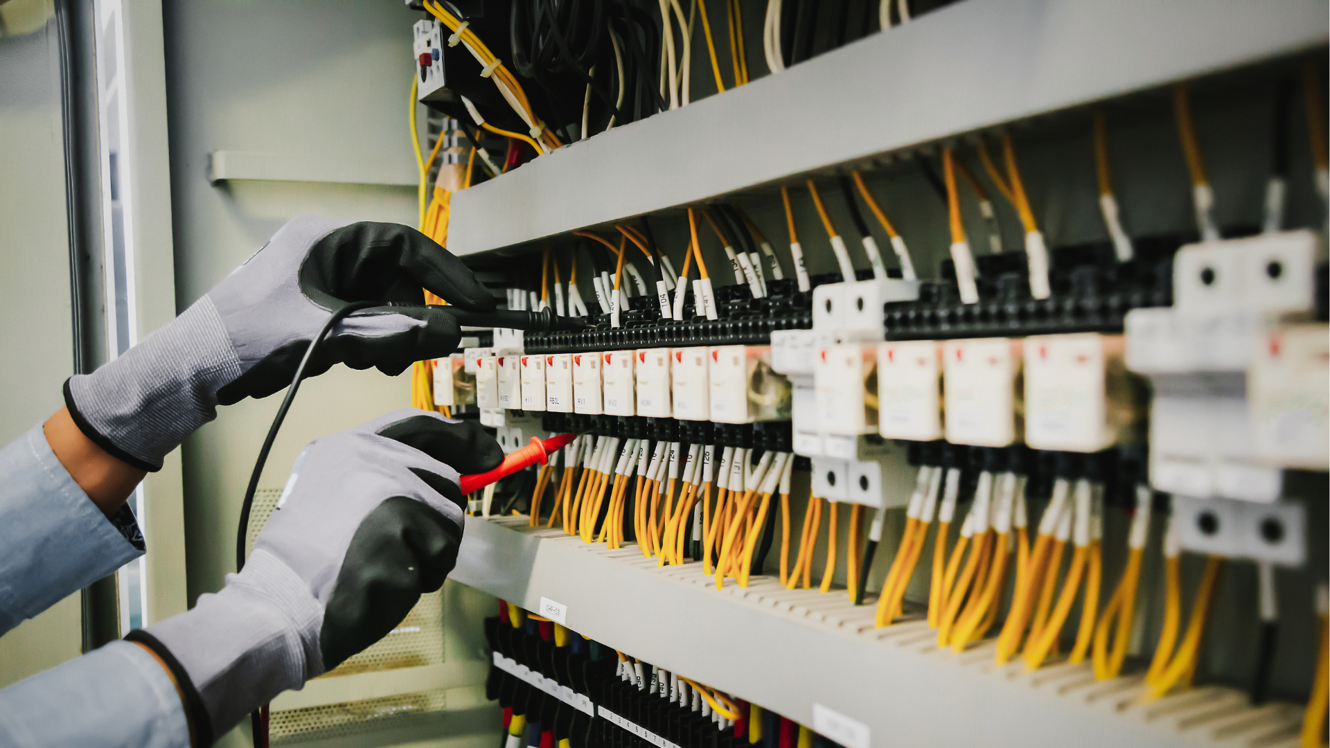 A person is working on an electrical panel in a factory.
