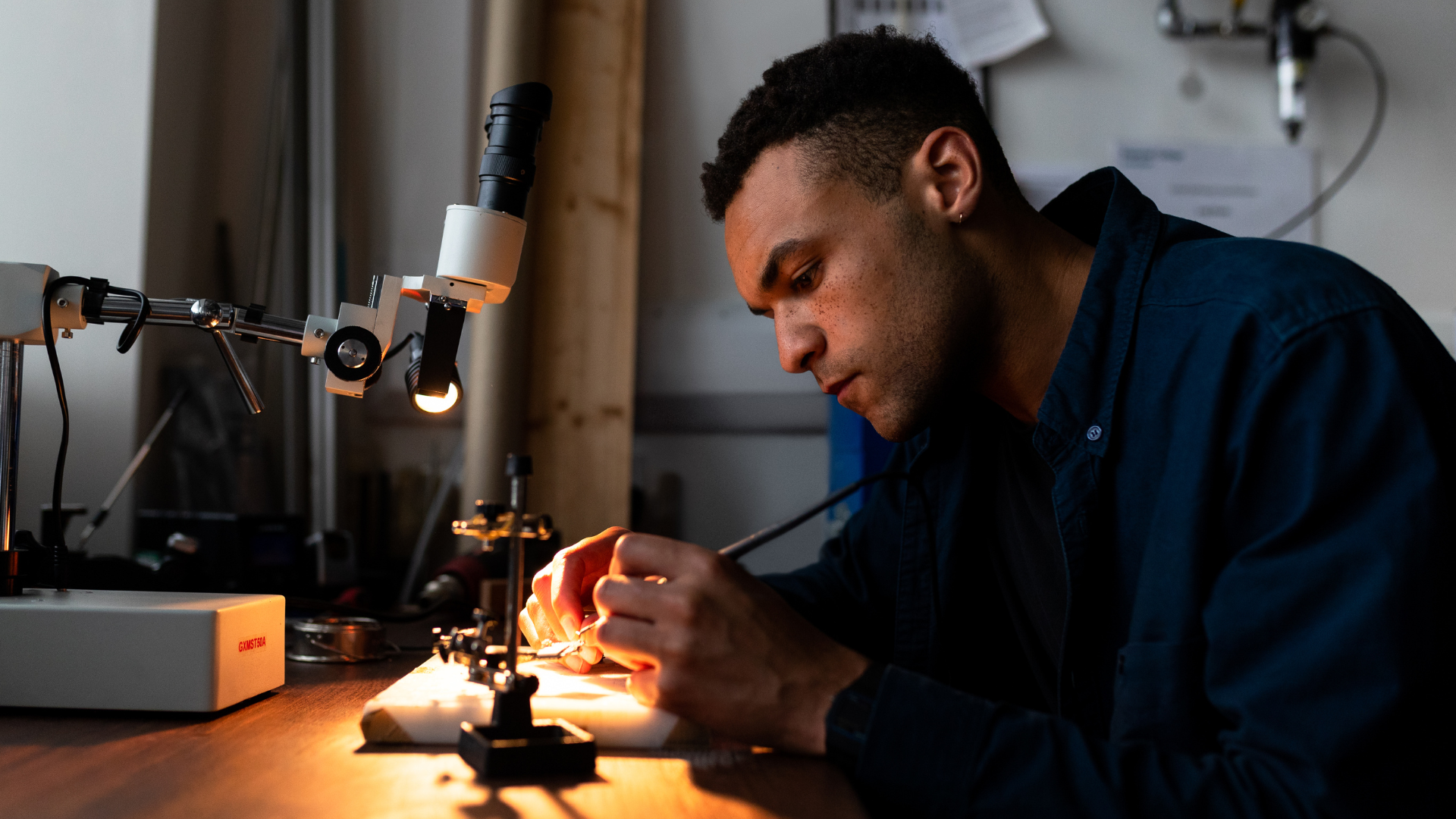 A man is working on a piece of equipment under a microscope.