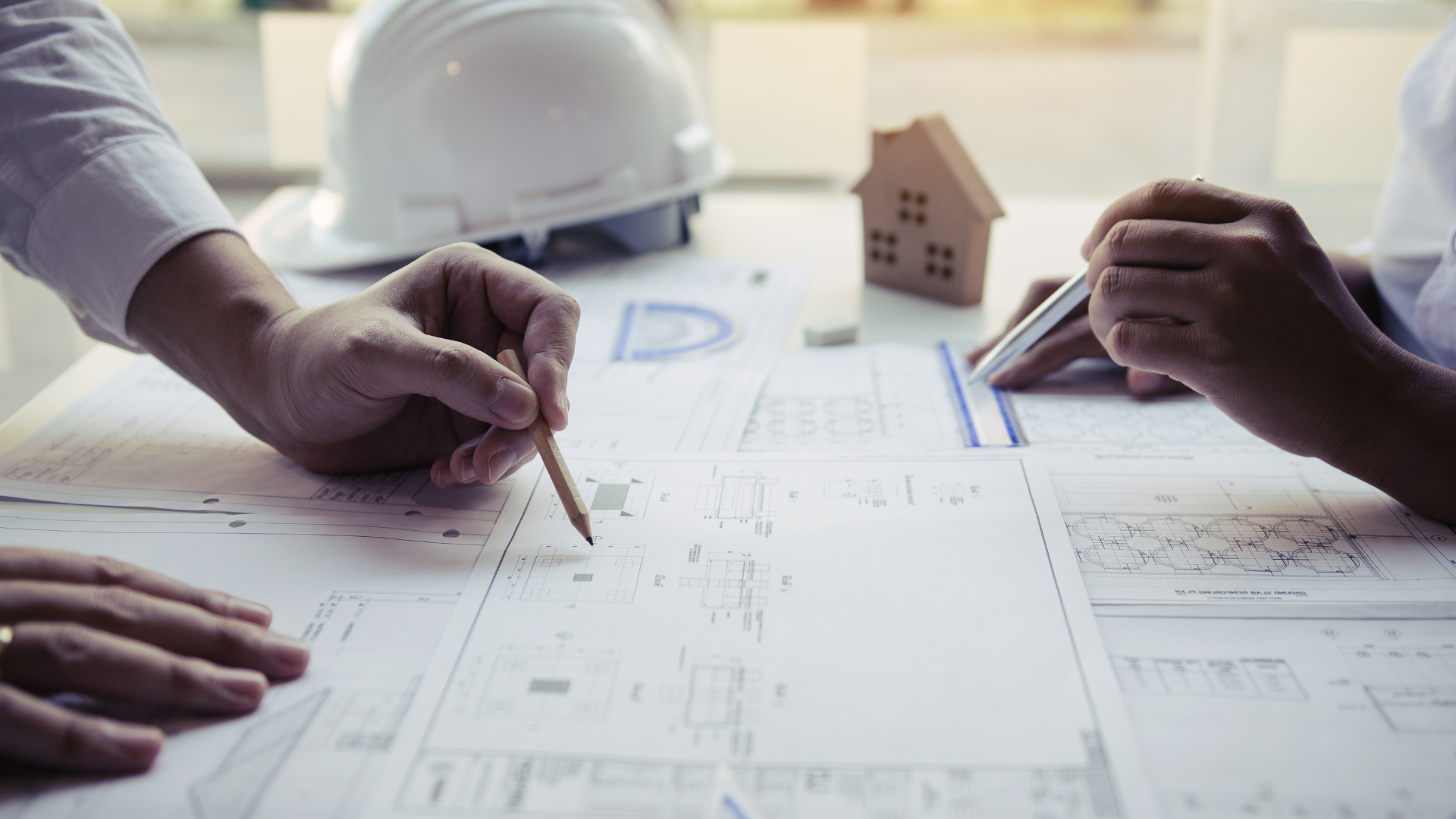 A couple of people are sitting at a table looking at a blueprint.