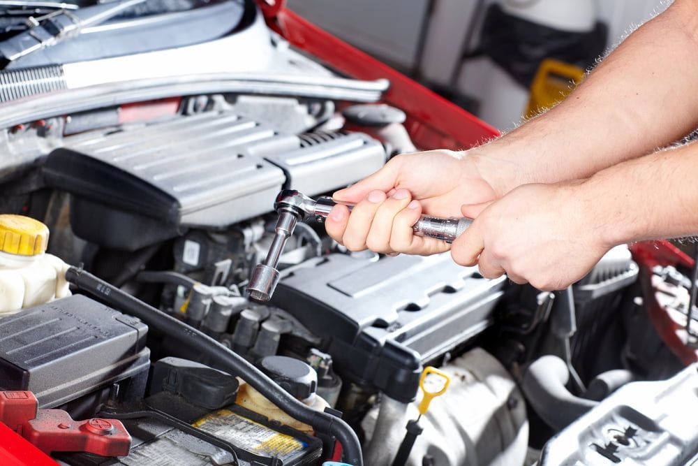 A Man Is Working On The Engine Of A Car With A Wrench — Josh's Diesel Services in Boyne Island, QLD
