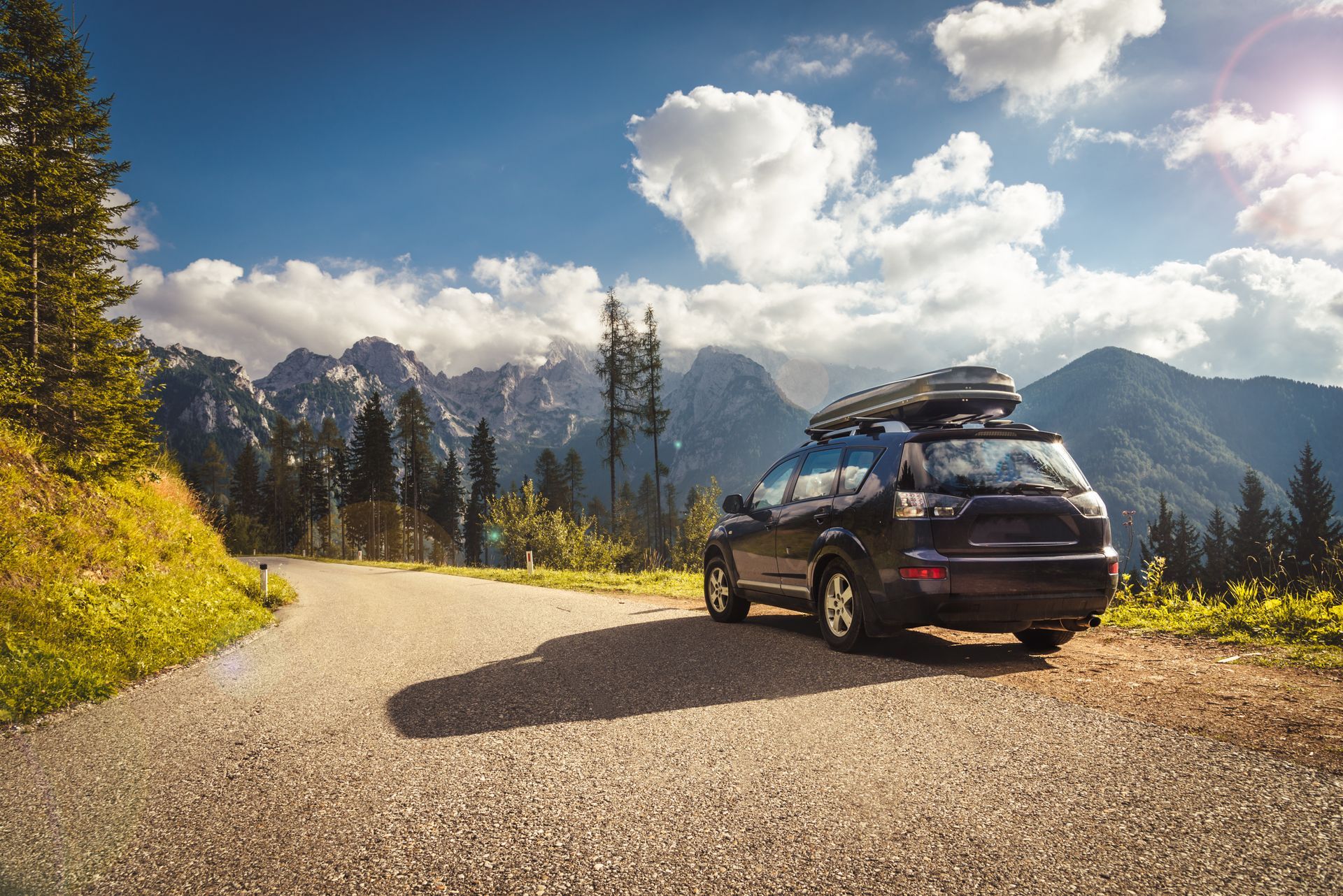 A car with a roof rack on top of it is parked on the side of a road.