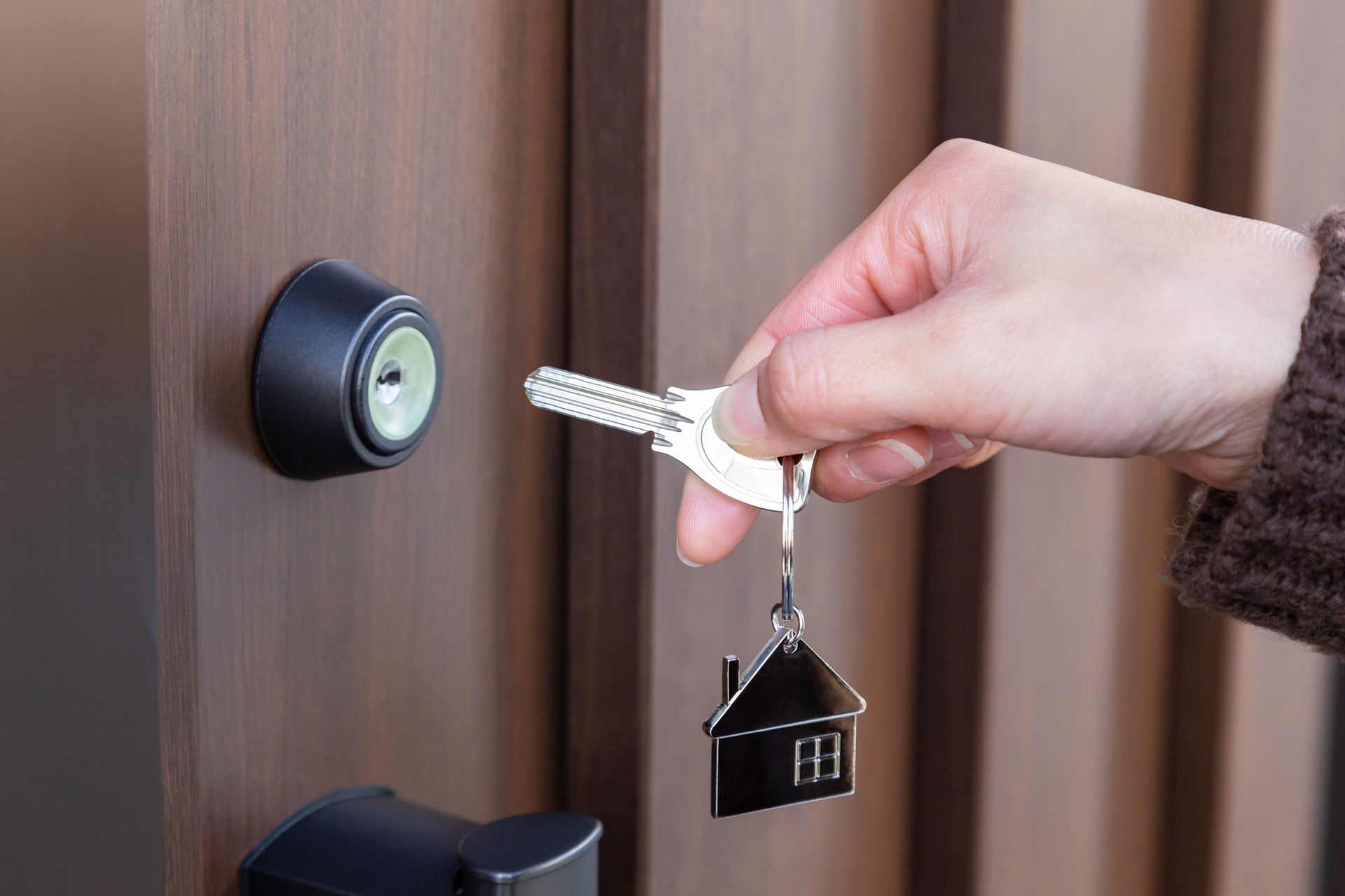 Una persona sostiene una llave en la mano delante de una puerta.