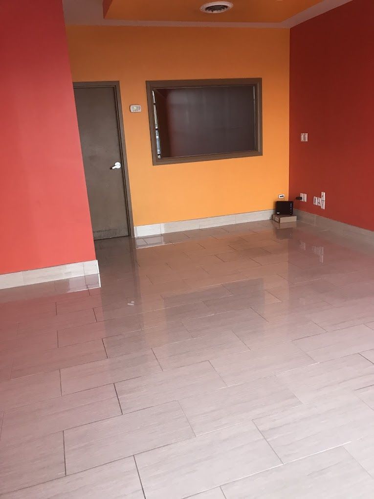 An empty room with red and orange walls and a white tile floor