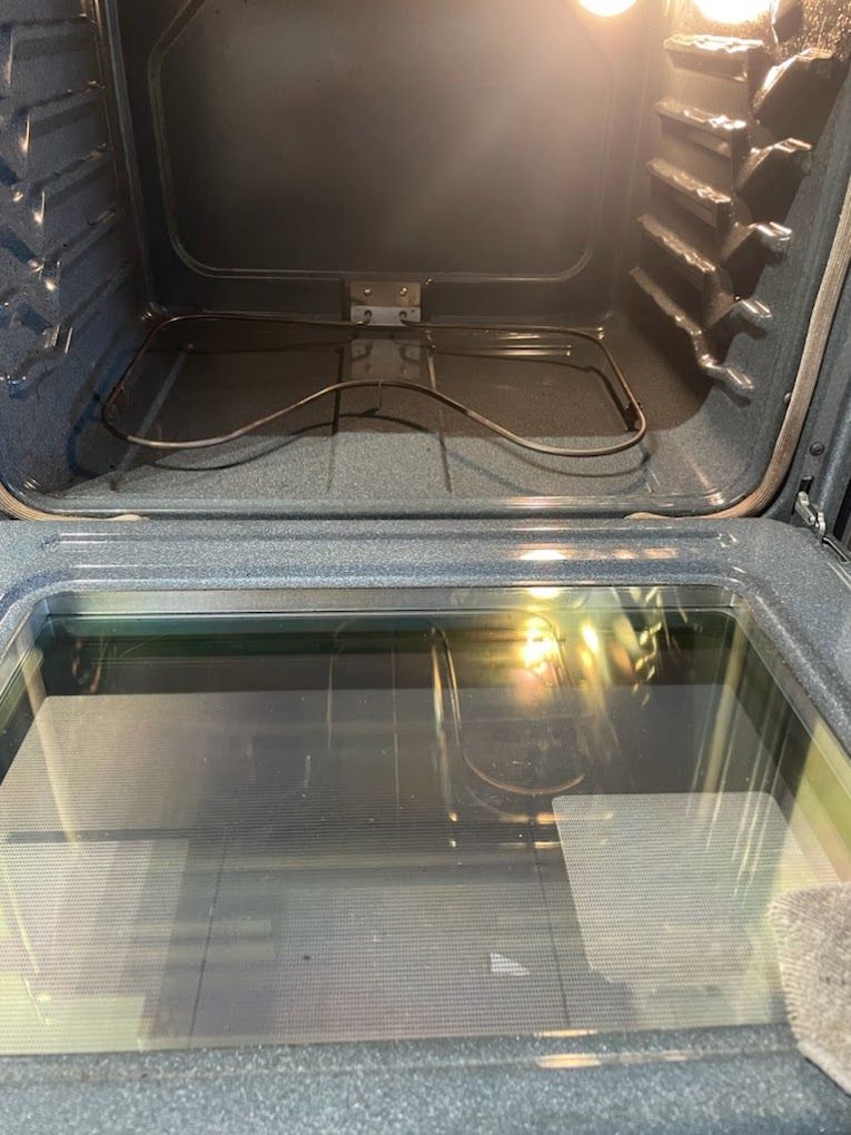 The inside of an oven with the door open and the lights on.