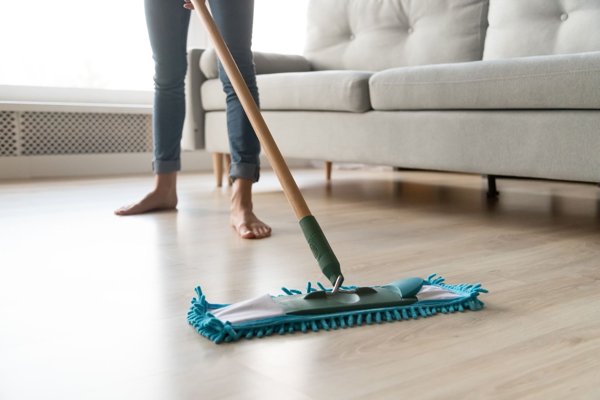 A woman is cleaning the floor with a mop in a living room.