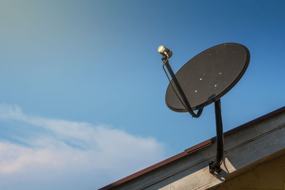 A Satellite Dish Mounted on a Rooftop Against — BTV Antenna & Data in Childers, QLD