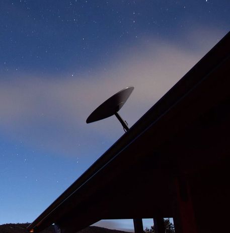 A Satellite Dish on Top of A Roof with The Sun Shining Through the Clouds — BTV Antenna & Data in Coral Cove, QLD