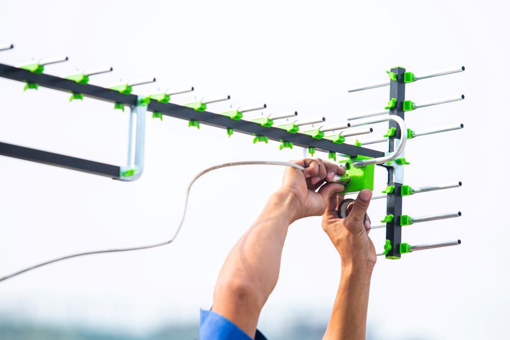 A Person Installing an Outdoor TV Antenna — BTV Antenna & Data in Woodgate, QLD