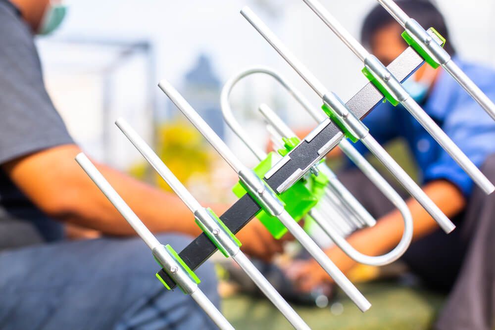A Man Is Sitting on The Ground Fixing an Antenna — BTV Antenna & Data in Burnett Heads, QLD