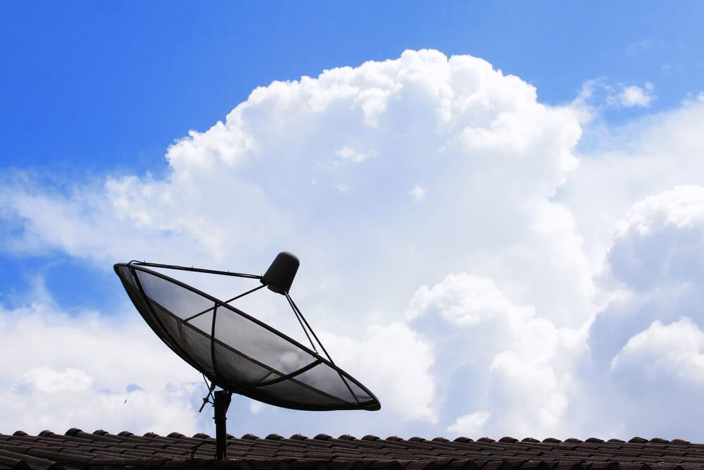 A Satellite Dish Is Sitting on Top of A Roof with A Cloudy Sky in The Background — BTV Antenna & Data in Coral Cove, QLD