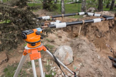 A level is sitting on top of a tripod in the dirt.