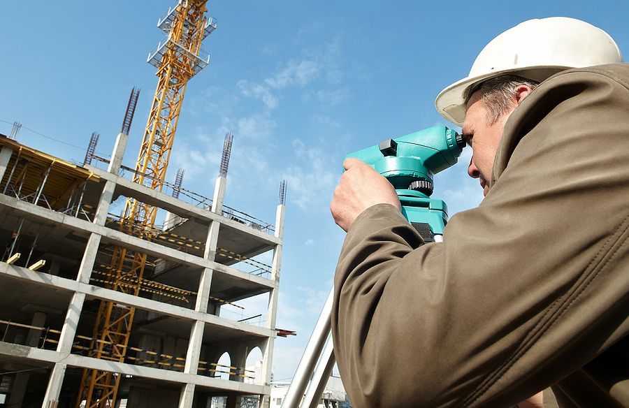A man is looking through a telescope at a building under construction.