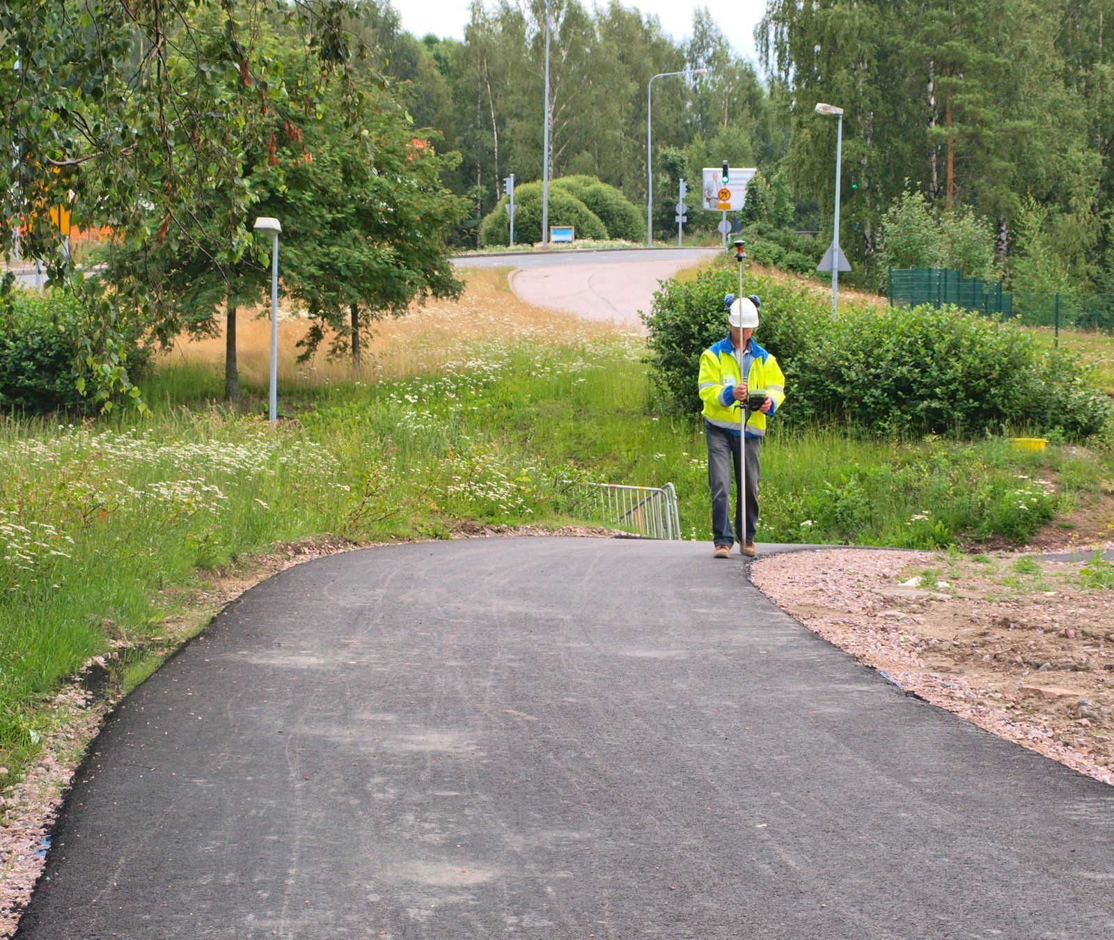 A man wearing a hard hat is walking down a road