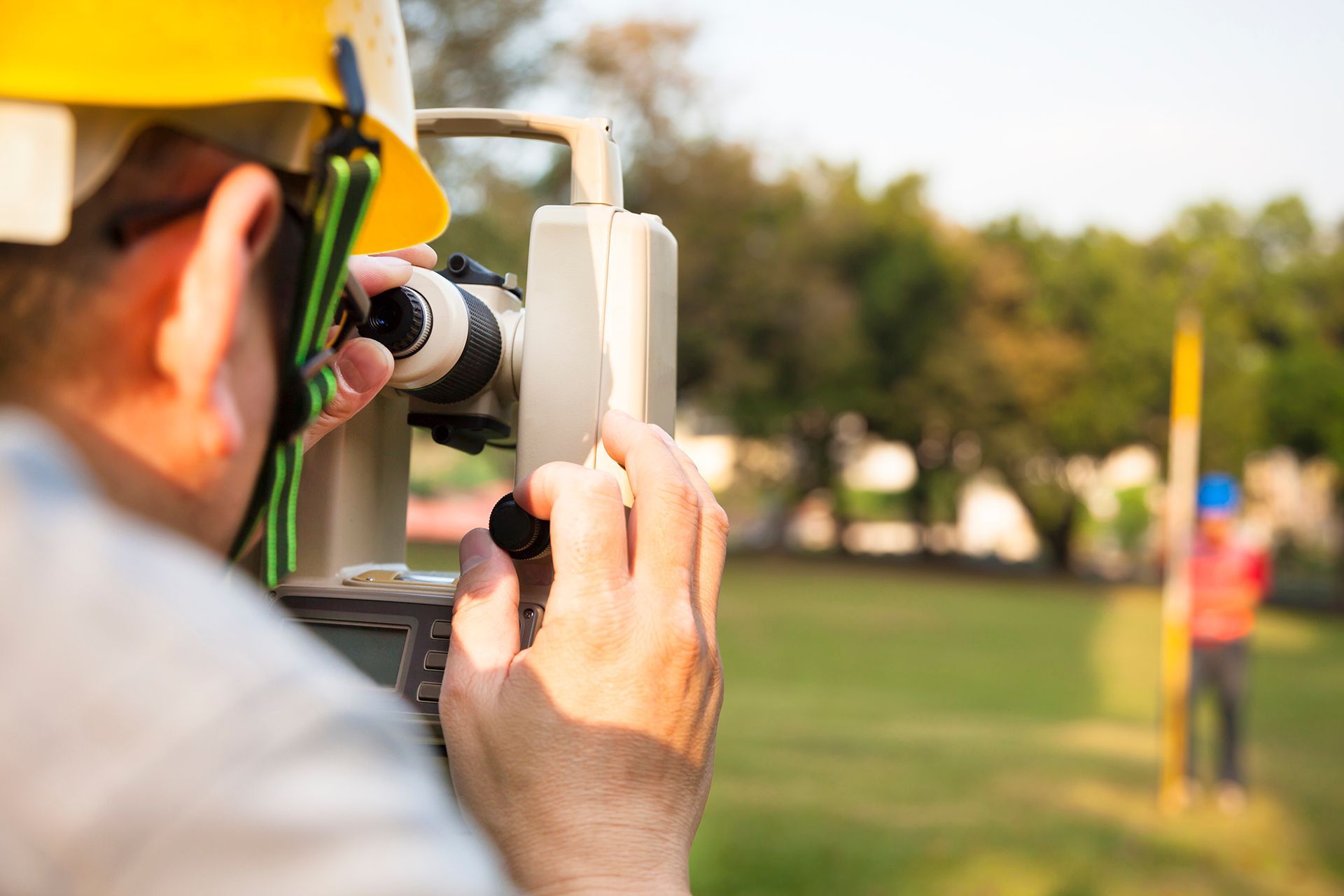 A man is using a theodolite to measure a field.